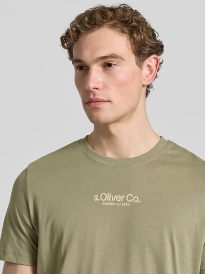 Męski model nosi Regular Fit T-Shirt aus reiner Baumwolle von s.Oliver RED LABEL, jednokolorowy, krój regular fit, nadruk z logo, okrągły dekolt, krótki rękaw, bawełna; zbliżenie na górę ciała