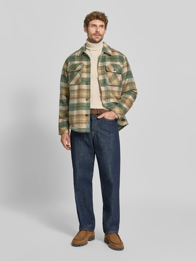 Männermodel trägt Regular Fit Hemdjacke mit Brusttaschen von Scotch & Soda im karierten Allover-Look, dezente Grüntöne, Ganzkörperansicht von vorne.