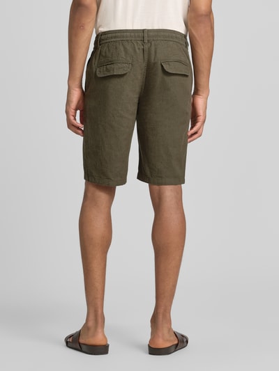 Männermodel trägt Bermudas aus Leinen-Mix mit französischen Eingrifftaschen von Lindbergh in Olive, Struktur sichtbar, Ganzkörperansicht Rückansicht, Leinen-Baumwoll-Mix, Straight Fit, elastischer Bund mit Kordelzug, Knopf- und Reißverschluss, Gesäßtaschen, Bundweite bei Größe M 43 cm, Innenbeinlänge 24 cm.