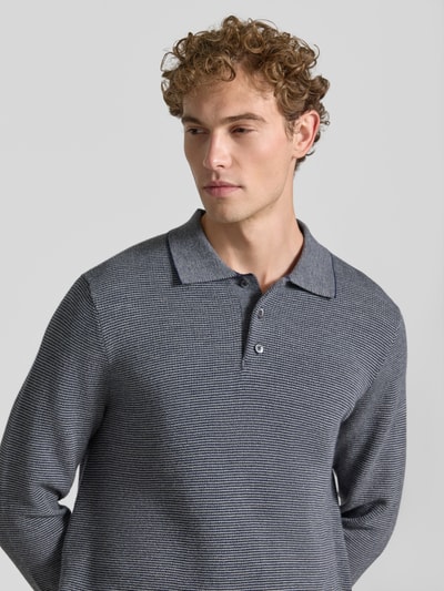 Mężczyzna nosi Regular Fit Poloshirt mit Woll-Anteil od Polo Ralph Lauren, odcienie szarości, delikatna faktura, zbliżenie na górną część ciała.