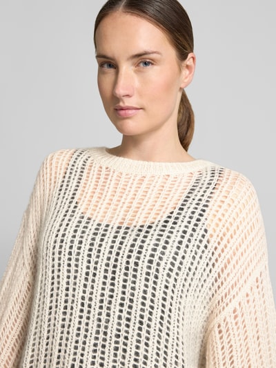 Frauenmodel trägt Loose Fit Pullover aus Woll-Mix von BOSS Orange in Creme mit transparenter Strickstruktur, Nahaufnahme Oberkörper.