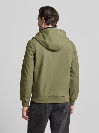 Männermodel trägt Regular Fit Funktionsjacke mit Kapuze von Tom Tailor Denim in Oliv, unifarben, langarm, elastische Abschlüsse, wasserdicht, Ganzkörperansicht Rückansicht.