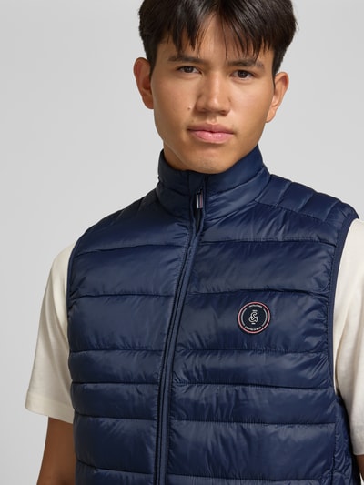 Männermodel trägt donkerblau bodywarmer Model 'KINGSLEY' van JACK & JONES met opstaande kraag en ritszakken, regular fit, Nahaufnahme Oberkörper. Ruglengte maat M: 65 cm, schouderbreedte 42 cm, borstwijdte 43 cm.