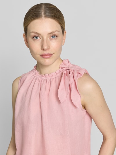 Frauenmodel trägt Regular Fit Bluse aus Viskose-Mix mit Leinen-Anteil von Christian Berg Woman in Rosa, Zierschleife, Stehkragen mit Rüschenbesatz, Ärmelloses-Design, Nahaufnahme Oberkörper.