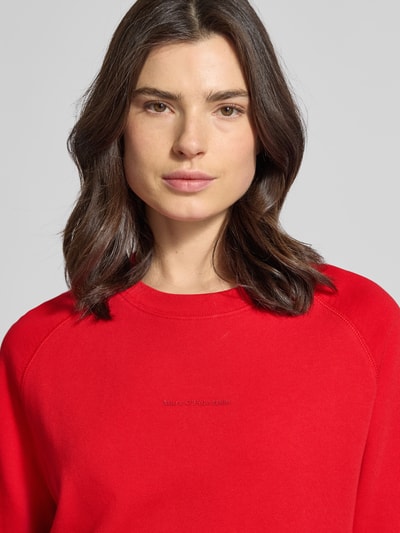 Modelka kobieca nosi Regular Fit Sweatshirt aus reiner Baumwolle od Marc O'Polo Denim, efekt: jednolity kolor, nadruk z logo, dekolt okrągły, długi rękaw, zakończenia prążkowane, rozcięcia boczne, bawełna, zbliżenie na górną część ciała.