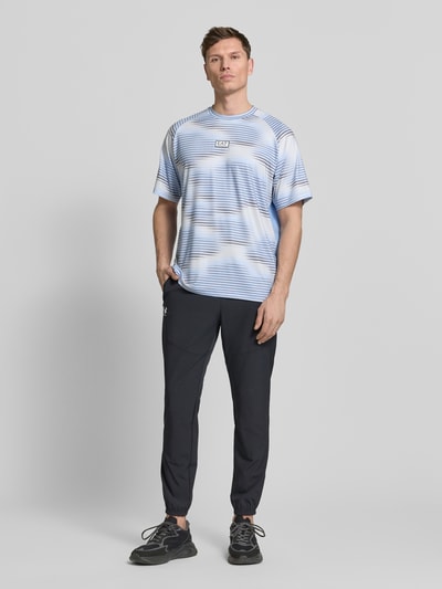 Männermodel trägt Regular Fit T-Shirt mit Logo-Applikation von EA7 Emporio Armani, hellblau mit weißen und blauen Streifen, Rundhalsausschnitt, elastischer Material-Mix, Ganzkörperansicht von vorne.