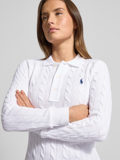 Frauenmodel trägt Strickpullover mit Zopfmuster und Polokragen von Polo Ralph Lauren, Reine Baumwolle, Slim Fit, Label-Stitching, weiße Farbe, Knopfleiste, Nahaufnahme Oberkörper.