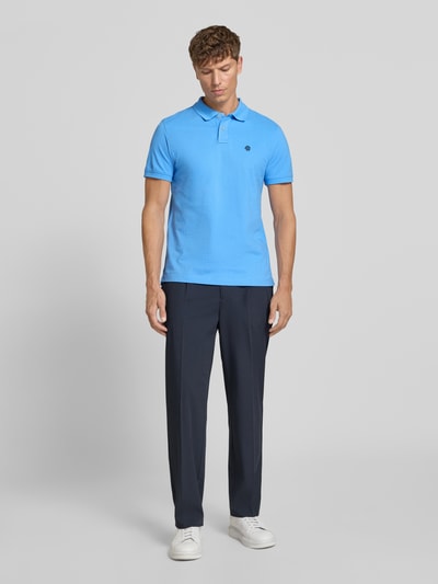 Männermodel trägt Slim Fit Poloshirt mit Label-Stitching von MCNEAL aus Reine Baumwolle, leuchtend blau, Ganzkörperansicht von vorne.
