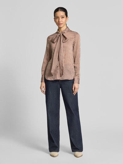 Frauenmodel trägt Regular Fit Schluppenbluse Modell 'CORBAT' von Mango aus Lyocell-Mix im Allover-Look, Rückenlänge 65 cm, Ärmellänge 61 cm, Ganzkörperansicht von vorne.