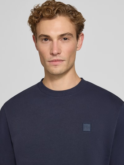 Männermodel trägt Regular Fit Sweatshirt aus reiner Baumwolle mit Label-Patch von Scotch & Soda, dunkelblau, Nahaufnahme Oberkörper, elastische Abschlüsse, Kontext Herren Sweatshirt Rückenlänge 70 cm Ärmellänge 66 cm.