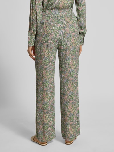 Frauenmodel trägt Stoffhose aus Viskose im Allover-Look Modell 'Bala' von MOS MOSH, grün mit floralen Mustern, elastischer Bund, Ganzkörperansicht Rückansicht.