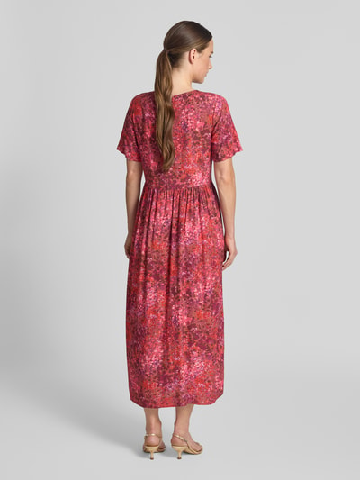 Frauenmodel trägt Midikleid aus Viskose im Allover-Look von Rich & Royal, rote und pinke Farbtöne, A-Linie, Ganzkörperansicht Rückansicht.