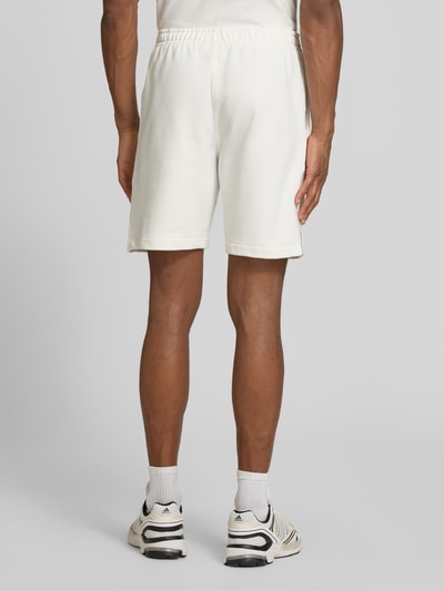 Männermodel trägt Regular Fit Sweatshorts aus reiner Baumwolle von Lacoste, unifarben, elastischer Bund, Rückansicht Ganzkörperansicht.