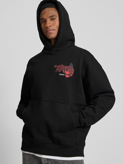 Männermodel trägt Regular Fit Hoodie aus reiner Baumwolle Modell 'DAGETHOOD' von HUGO, Optik: Unifarben, Motiv-Print, Ganzkörperansicht von vorne.