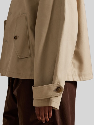 Vrouwenmodel draagt Regular Fit Trenchcoat uit pure katoen van Polo Ralph Lauren in effen beige, detailopname mouw en zak.