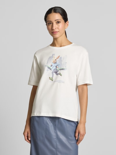 Frauenmodel trägt T-Shirt mit Motiv-Print von Marc Cain in Weiß, lockerer Schnitt, reine Baumwolle, Rundhalsausschnitt, Ganzkörperansicht von vorne.