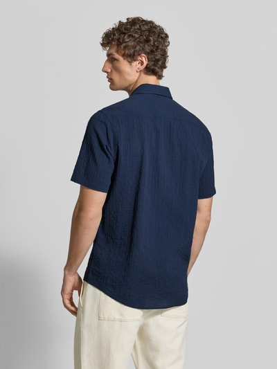 Männermodel trägt Relaxed Fit Freizeithemd mit Logo-Stitching und Kentkragen von Lerros aus dunkelblauem Seersucker, Ganzkörperansicht Rückansicht. Rückenlänge bei Größe M: 75 cm, Schulterbreite bei Größe M: 45 cm, Ärmellänge bei Größe M: 25 cm, abgerundeter Saum, Knopfleiste.