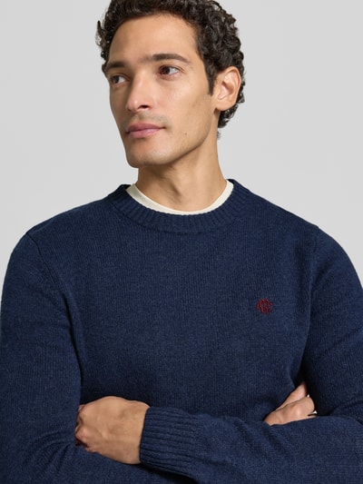 Männermodel trägt Slim Fit Strickpullover aus reiner Wolle mit Label-Stitching von MCNEAL, marineblau, Nahaufnahme Oberkörper. Rückenlänge 66 cm, Ärmellänge 69 cm, gerippte Abschlüsse.