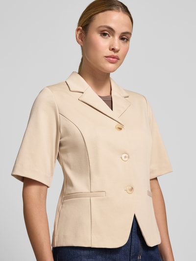 Frauenmodel trägt Blazer mit Viskose-Anteil Modell 'Kate' von ICHI in Beige, Elastischer-Material-Mix, Reverskragen, Halbarm, Paspeltaschen, durchgehende Knopfleiste, taillierte Passform, Nahaufnahme Oberkörper.