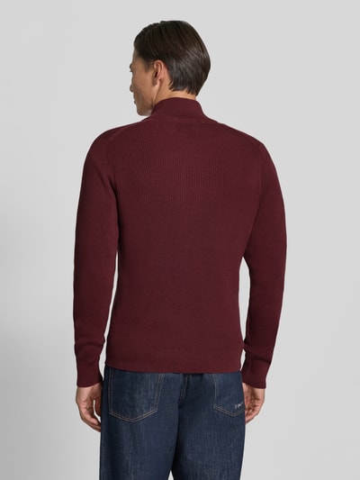 Männermodel trägt Strickjacke mit Stehkragen Modell 'LEVI' von MCNEAL aus Baumwoll-Mix in Dunkelrot, gerader Schnitt, Ganzkörperansicht Rückansicht.