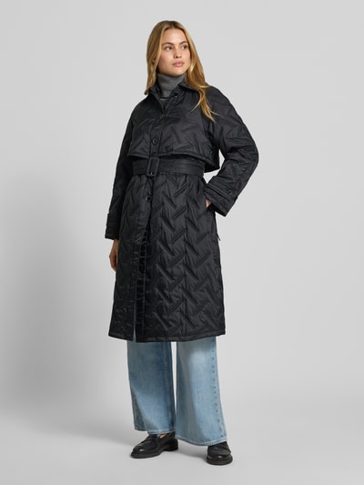 Frauenmodel trägt Regular Fit Mantel in Stepp-Optik von Emporio Armani in Schwarz, mit Gürtel und Kapuze, Ganzkörperansicht von vorne.