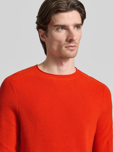 Männermodel trägt Strickpullover aus Baumwoll-Kaschmir-Mix mit gerippten Abschlüssen von FTC-Cashmere, leuchtend rot, Nahaufnahme Oberkörper.