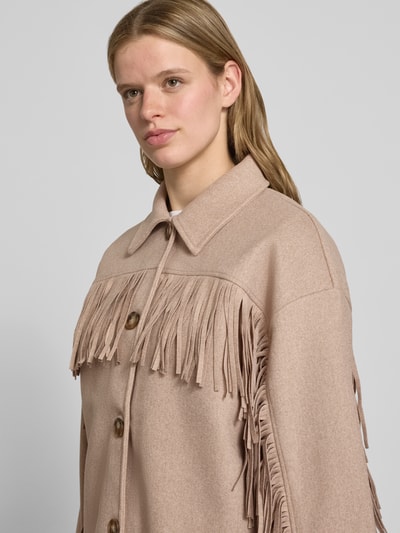 Frauenmodel trägt Relaxed Fit Jacke mit Umlegekragen von Gina Tricot in Beige mit Fransenbesatz und durchgängiger Knopfleiste, Nahaufnahme Oberkörper. Rückenlänge 76 cm, Schulterbreite 56 cm, Brustweite 57 cm, Ärmellänge 54 cm, Größe S.
