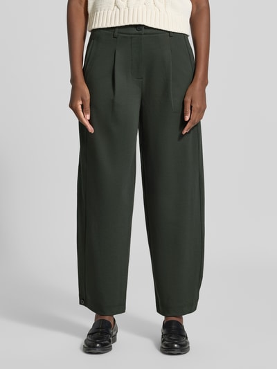 Frauenmodel trägt Wide Fit Hose mit Viskose-Anteil Modell 'Nanni' von FREE/QUENT in Dunkelgrün mit Bundfalten, Ganzkörperansicht von vorne. Elastischer Material-Mix, Knopf- und Reißverschluss, Bundweite und Innenbeinlänge laut Größe S.