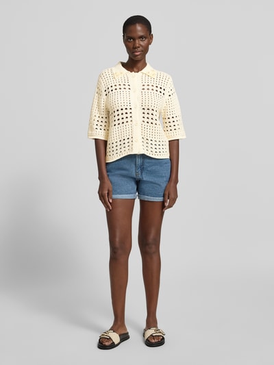 Frauenmodel trägt Regular Fit Bluse in Strick-Optik mit floralem Ziersteinbesatz von Liu Jo White aus reiner Baumwolle, Lochmuster, Halbarm, Umlegekragen, durchgängige Knopfleiste, helle Cremefarbe, strukturierte Textur, Ganzkörperansicht von vorne.