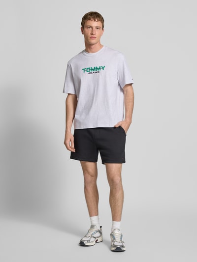 Männermodel trägt Regular Fit T-Shirt aus reiner Baumwolle von Tommy Jeans, Optik: Unifarben, Label-Schriftzug, Ganzkörperansicht von vorne.