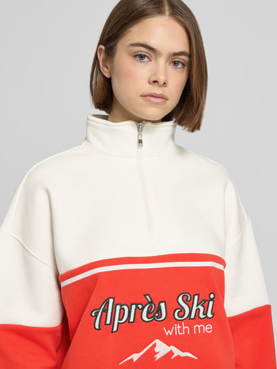 Frauenmodel trägt Relaxed Fit Sweatshirt mit Stehkragen Modell 'Jenny' von LeGer by Lena Gercke in Creme und Rot, Stitchings, Reißverschluss, Nahaufnahme Oberkörper.