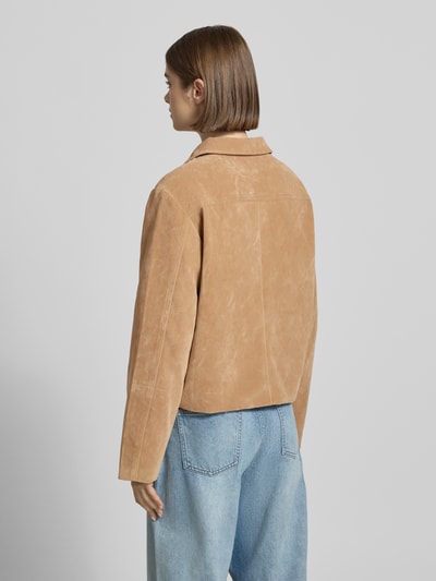 Frauenmodel trägt Jacke in Leder-Optik mit Kentkragen Modell 'Trine' von Gina Tricot, Material-Mix mit Viskose-Anteil, Gerader-Schnitt, Rückenlänge 55 cm, Schulterbreite 44 cm, Brustweite 51 cm, Ärmellänge 62 cm, hellbraune Farbe, glatte Textur, kombiniert mit blauer Jeans, Ganzkörperansicht Rückansicht.