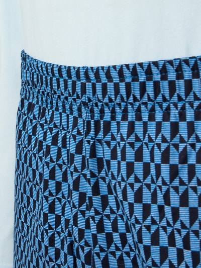 Männermodel trägt Pyjama mit klassischer Brusttasche und Rundhalsausschnitt von Schiesser, geometrisches Muster in Blau und Schwarz, Reine Baumwolle, komfortabler Schnitt für mehr Bewegungsfreiheit, elastischer Bund, Detailaufnahme Taille.