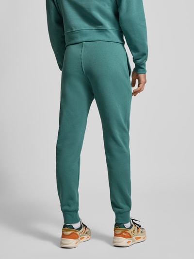 Männermodel trägt Sweatpants mit elastischem Bund und Label-Stitching von CHAMPION in Türkis, Baumwoll-Mix, Regular-Fit, Rückansicht Ganzkörperansicht. Innenbeinlänge bei Größe M: 76 cm.