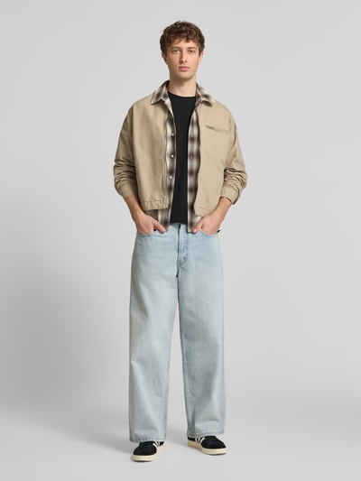 Männermodel trägt T-Shirt mit Label-Patch von Alpha Industries aus reiner Baumwolle, Gerader-Schnitt, Schwarz, Ganzkörperansicht von vorne.