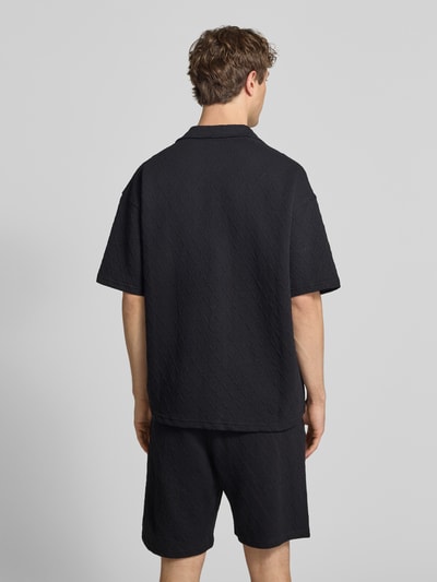 Männermodel trägt zwart heren vrijetijdsoverhemd van Pegador model 'Jovren', regular fit, elastische materiaalmix met katoen, halflange mouwen, reverskraag, knoopsluiting, labelstitching, ruglengte maat M 72 cm, schouderbreedte 45 cm, mouwlengte 33 cm, textuur met ruitpatroon, effen kleur, ganzekörper Ansicht rückansicht.