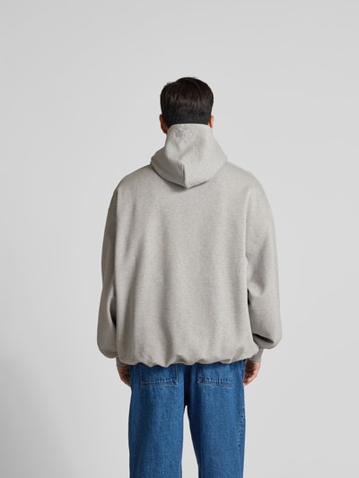 Männermodel trägt Oversized Hoodie mit Motiv-Print von VETEMENTS in Grau, Baumwoll-Mix, strukturierte Oberfläche, Rückansicht Ganzkörperansicht.