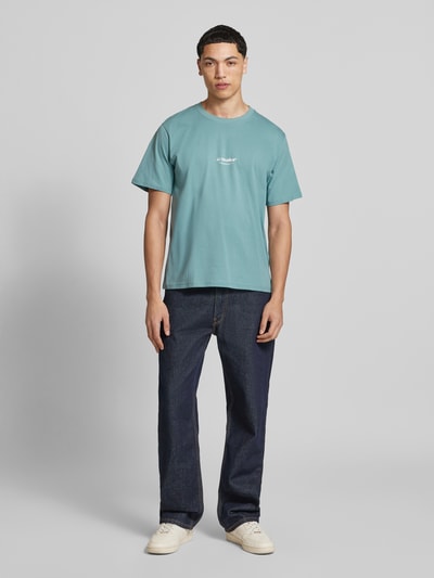 Männermodel trägt T-Shirt mit Logo und Rundhalsausschnitt von Jack & Jones, Bio-Baumwolle, Regular Fit, blaue Farbe, Ganzkörperansicht von vorne