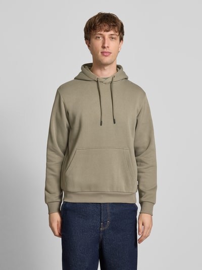 Männermodel trägt Hoodie mit Kapuze Modell 'BRADLEY' von Jack & Jones in Beige, Kängurutasche, gerippte Abschlüsse, Ganzkörperansicht von vorne.
