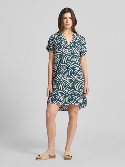 Männermodel trägt Relaxed Fit Kleid aus reiner Viskose Modell 'Mary' von ZABAIONE, floraler Allover-Print, tunika-ausschnitt, kurzärmelig, Rückenlänge 94 cm, Szerokość w rozmiarze S: 52 cm, długość rękawa 18 cm, kombinacja granatowych i beżowych odcieni, lekka tekstura, Ganzkörperansicht von vorne.