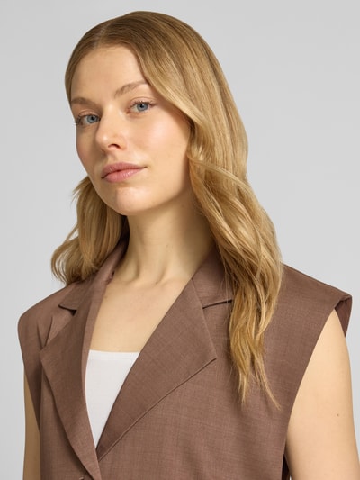 Vrouwenmodel draagt Regular Fit Blazer mit Paspeltaschen van Little Mistress in bruin, mouwloos design, reverskraag, knoopsluiting, paspelzakken, ruglengte bij maat 36: 70 cm, close-up bovenlichaam