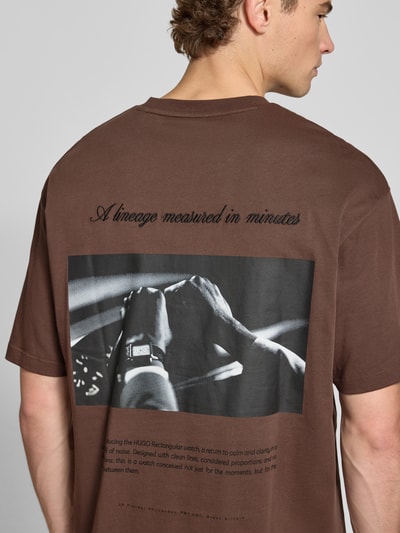 Männermodel trägt Oversized T-Shirt aus reiner Baumwolle Modell 'Devrolo' von HUGO in Braun mit Print, Ganzkörperansicht Rückansicht, Herren T-Shirt von HUGO