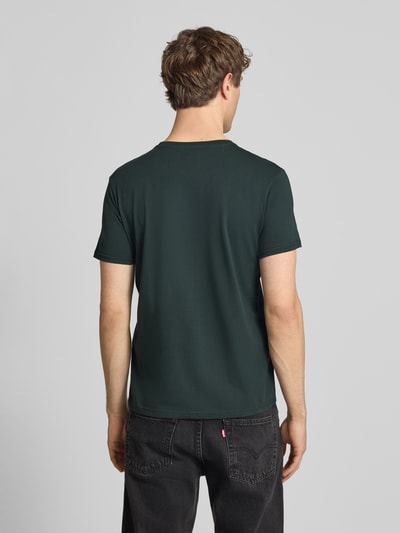 Männermodel trägt męski t-shirt z bawełny, prosty krój, okrągły dekolt, detal z logo, model 'BASIC' od Alpha Industries, długość tyłu w rozmiarze M 69 cm, Ganzkörperansicht Rückansicht