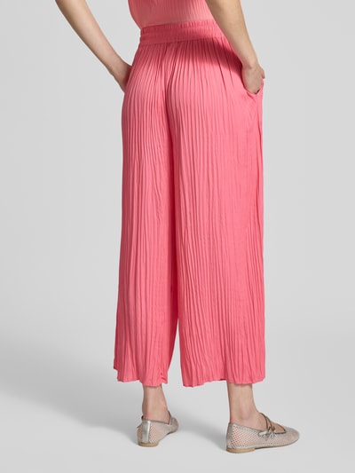 Frauenmodel trägt Pull-on-Hose mit Plisseefalten mit Tunnelzug von Marc Cain in Pink, Relaxed-Fit, Label-Detail, Ganzkörperansicht Rückansicht.