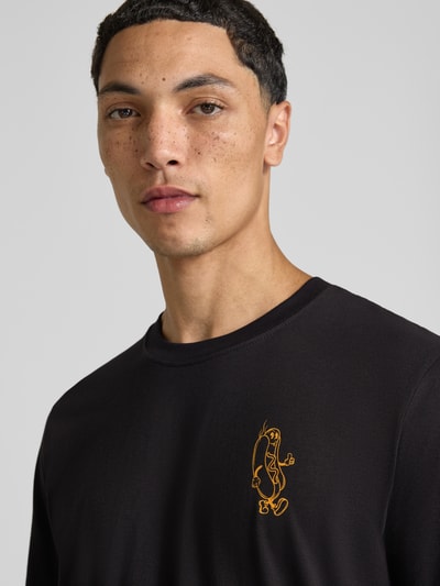 Męski model nosi Regular Fit T-Shirt aus reiner Baumwolle Modell 'BREWY' od JACK & JONES, czarny, nadruk z napisem, kontekst: męski t-shirt z bawełny, krój regular fit, Długość tyłu w rozmiarze M: 68 cm, Nahaufnahme Oberkörper.