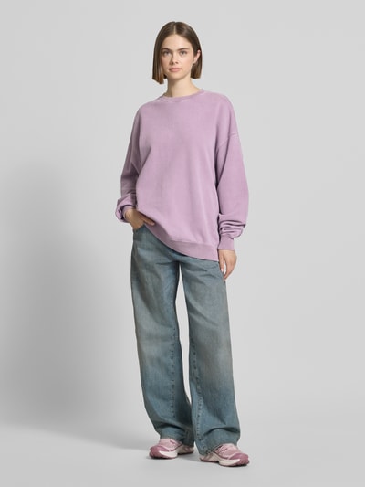 Frauenmodel trägt Oversized Sweatshirt mit Logo-Stitching Modell 'Farmers Market' von OH APRIL aus Reine Baumwolle in zartem Flieder mit Geripptem Rundhalsausschnitt, Überschnittene Schultern und rückseitigem Statement-Print, Oversized-Fit, Ganzkörperansicht von vorne.