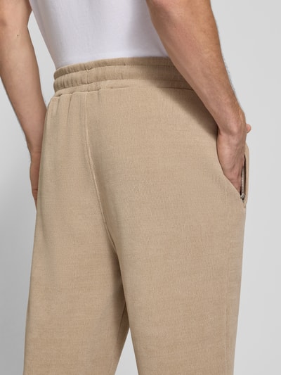 Männermodel trägt Wide Fit Sweatpants mit Label-Detail Modell 'Mezzano' von PEGADOR in Beige, elastischer Bund, Nahaufnahme Rückansicht, elastischer Material-Mix, Eingrifftaschen