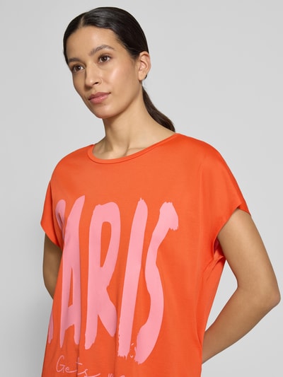 Frauenmodel trägt Oversized Fit T-Shirt aus Viskose-Mix von Smith & Soul in Orange mit pinkem Motiv-Print, Baumwoll-Viskose-Mix, Rundhalsausschnitt, Ganzkörperansicht von vorne.