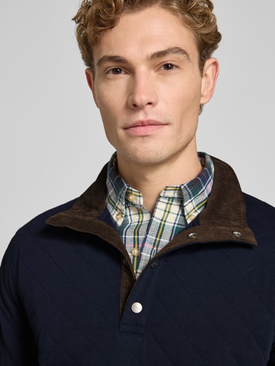 Männermodel trägt Regular Fit Troyer aus Baumwoll-Mix von GANT, jednokolorowy, struktura, aplikacja: naszywka z logo, stójka, wysokie zapięcie, długi rękaw, zakończenia prążkowane, wykończenie: dzianina dresowa, materiał: mieszanka bawełny, Nahaufnahme górnej części ciała.