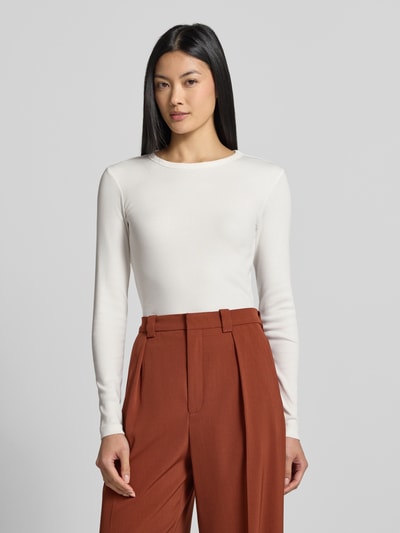 Frauenmodel trägt weißes Slim Fit Langarmshirt aus Baumwoll-Mix Modell 'CHLOE' von VERO MODA, kombiniert mit rostbrauner Hose, Ganzkörperansicht von vorne. Damen Langarmshirt von VERO MODA.